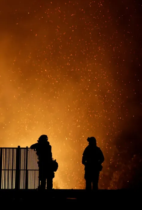Framed Print : Burning embers swirl around firefighters as they stand guard at a home while battling