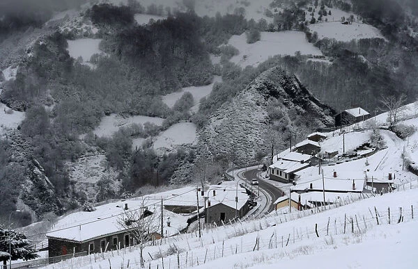 A car crosses the village of Pajares covered by snow