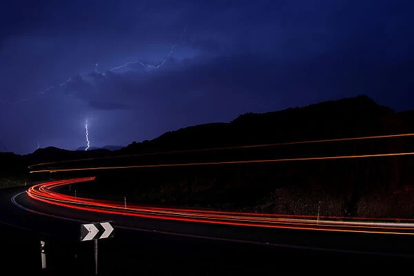 Cars drive as lightning strikes near the site where a group of Israeli youths was swept