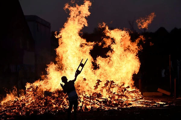 A child throws bits of wood onto a bonfire during the Twelfth of July celebrations held