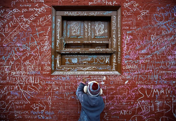 A child writes with chalk on a wall to celebrate Shreepanchami festival at Saraswati