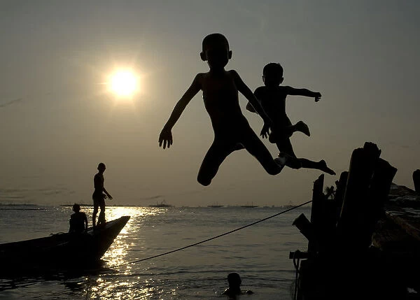 Children jump into the sea at Marunda beach in Jakarta