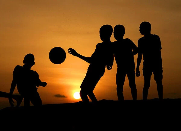 Children playing soccer are silhouetted at sunset in Nigerias main city of Lago