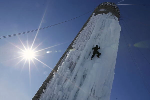 An climber ascends a silo covered in ice in Cedar Falls