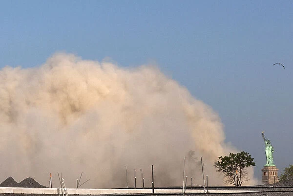 A cloud of dust from a nearby imploded building approaches the Statue of Liberty in New