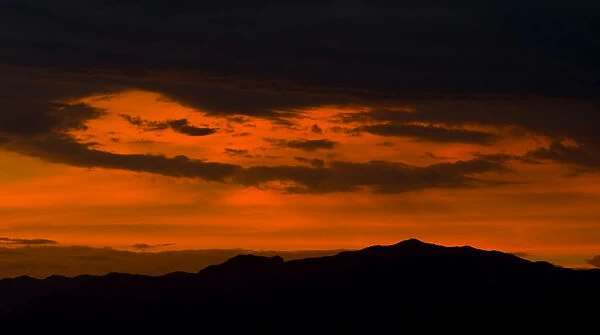 Clouds are lit up by a sunset over the Sheep Mountain Range north of Las Vegas