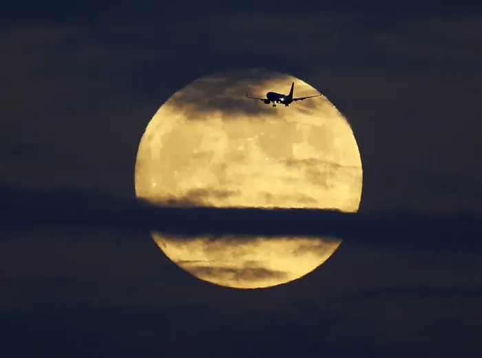 Framed Print : A commercial airliner crosses the path of a rising full moon as it comes in to land