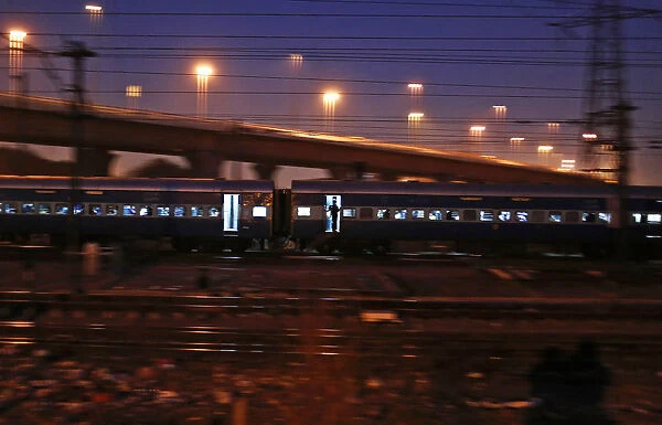 A commuter stands on the doorsteps of a moving train in New Delhi