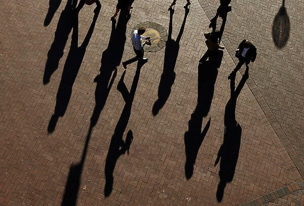 Commuters cast their shadows as they arrive at the Central Business District during