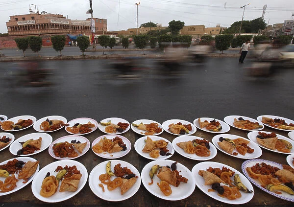 Commuters travel past plates of food, placed for passers-by to break their fast during
