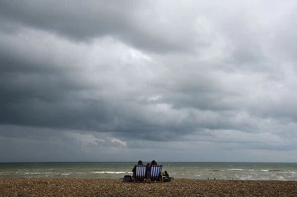 A couple sit on an almost deserted beach at Brighton in south east England