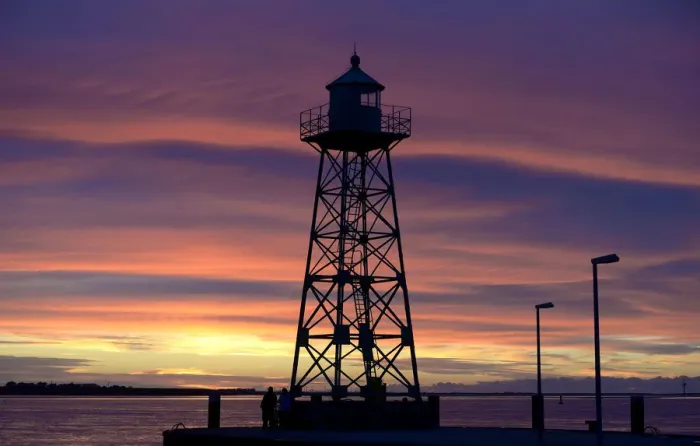 Framed Print : A couple stand beside a light house, which is silhouetted during sunset at the Weser Framed Print : A couple stand beside a light house, which is silhouetted during sunset at the Weser