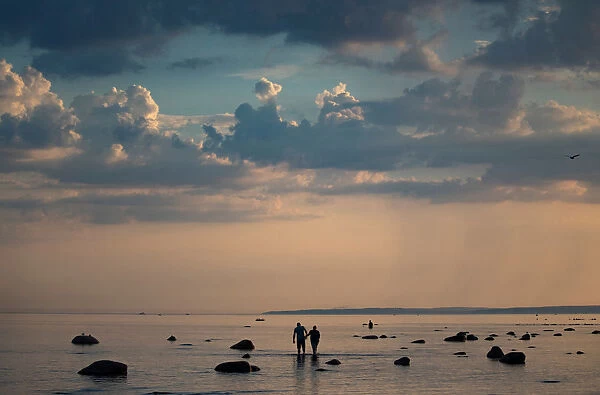 A couple walk in the Baltic Sea during sunset in Komarovo outside Saint Petersburg