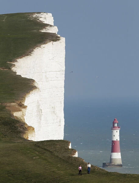 A couple walk along the Seven Sisters cliffs close to the Beachy Head lighthouse near Eastbourne