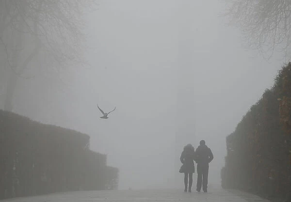 A couple walks in a park on a foggy winter day in central Kiev