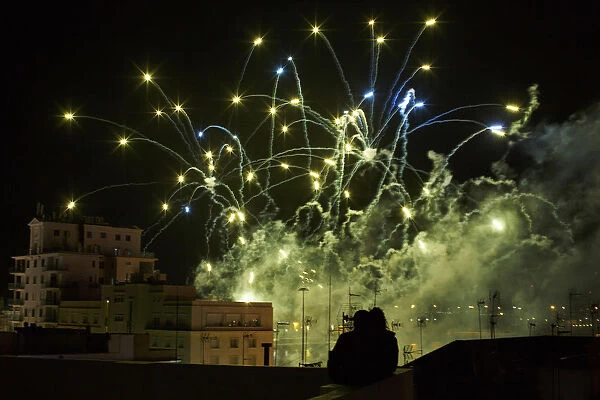 A couple watches fireworks from a terrace during the Carnival of Cadiz, southern Spain