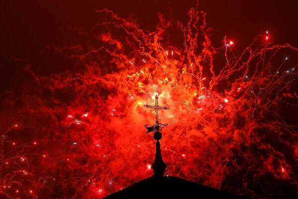 A cross of the Basilica of the Agustinas Recoletas is seen as fireworks explode over