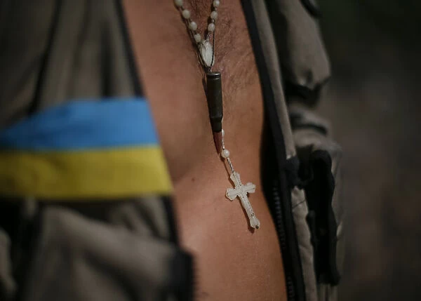 A cross and bullet are seen on Ukrainian serviceman as he stands in his camp near Donetsk