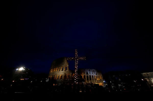A cross lit up with candles is seen in front of the Colosseum before the Via Crucis