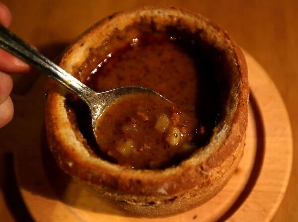 A customer eats a goulash soup from a bread bowl in a restaurant in Prague