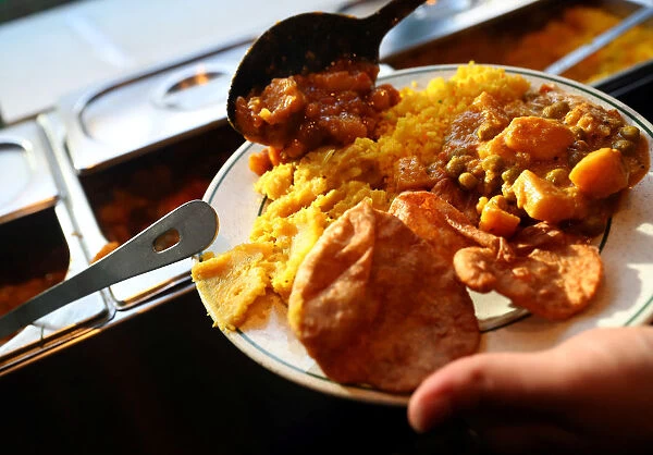 A customer self-serves a plate of food inside the Indian Veg vegetarian restaurant