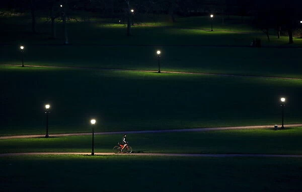 A cyclist rides through Primrose Hill in the early evening in London