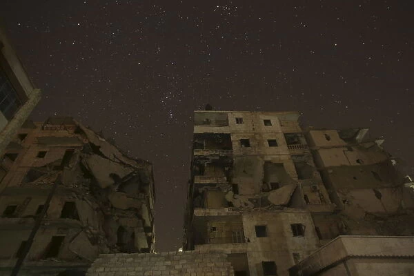 Damaged buildings are pictured at night in Aleppo, Syria