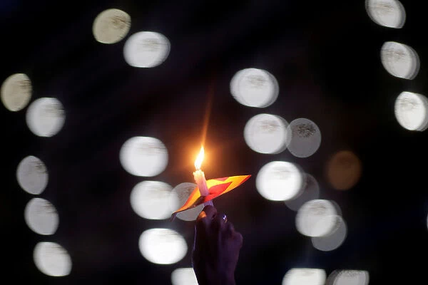 A demonstrator holds a candle as she takes part in a rally against the shooting of Rio de