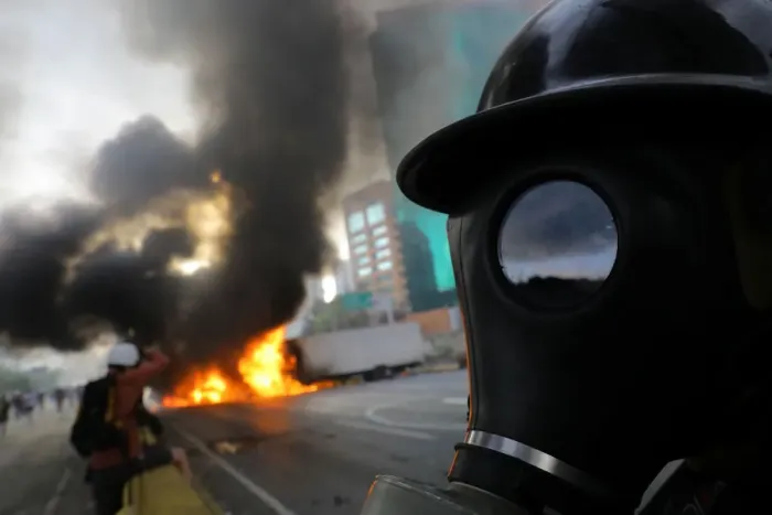 Framed Print : Demonstrators stand near burning trucks while rallying against President Nicolas Maduro