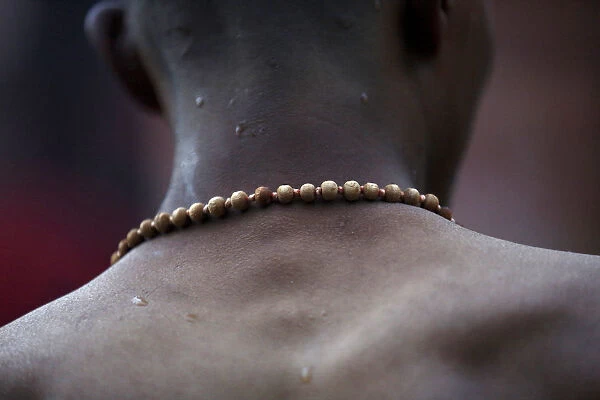 A devotee wearing prayer beads returns after taking a holy bath at the Saali River on the