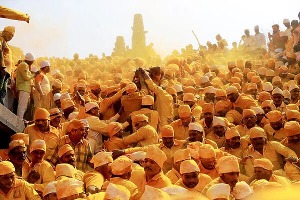 Devotees throw turmeric powder as an offering to the shepherd god Khandoba as others
