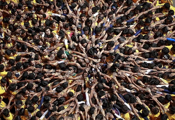 Devotees try to form a human pyramid to break a clay pot containing curd during celebrations