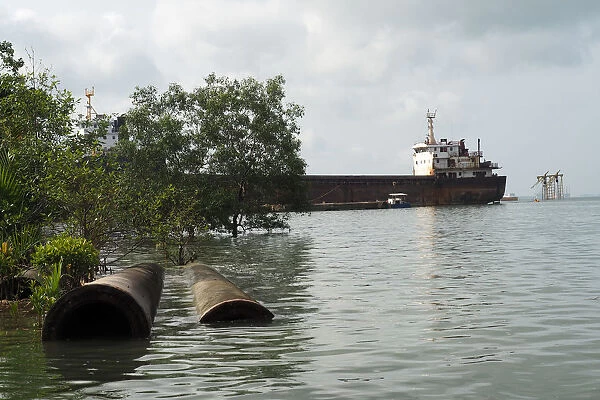 Disused pipes and a tanker sit in the Johor river