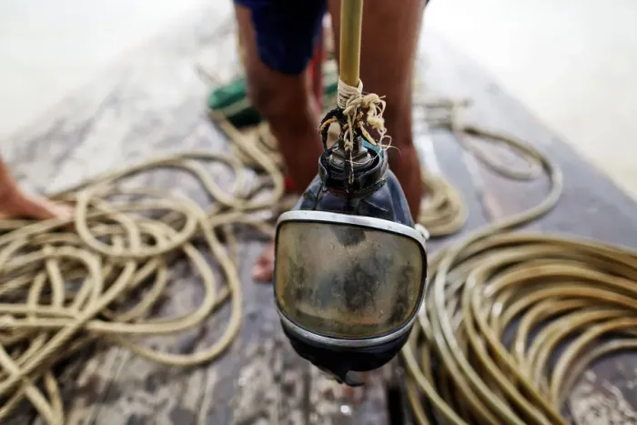 Framed Print : A diver holds his mask on a small boat on Yangon River after searching for coal