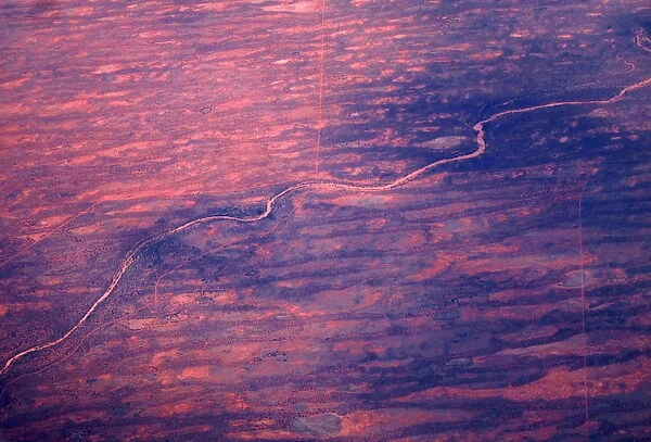 A dried-up river can be seen next to sand dunes and salt pans in outback Australia