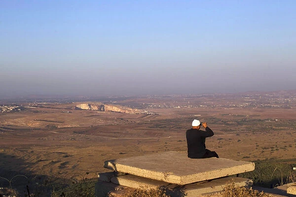 A Druze man uses binoculars as he looks towards Syria from part of an abandoned military
