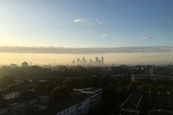 The early morning sun lights up the London skyline, seen from east London