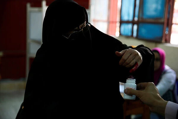 Egyptian woman has her finger stained with ink after casting her vote at a polling