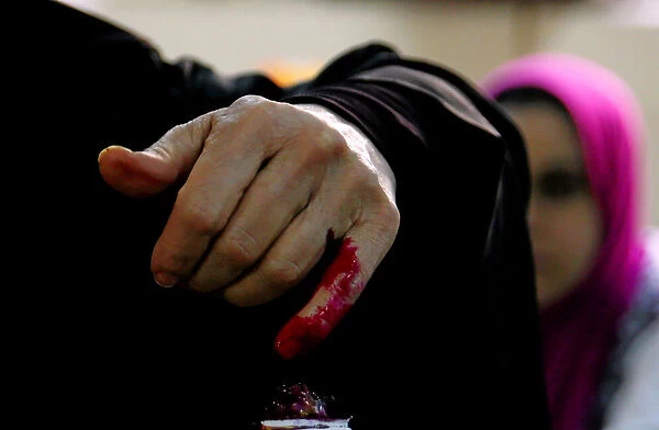 An Egyptian woman has her finger stained with ink after casting her vote during the first