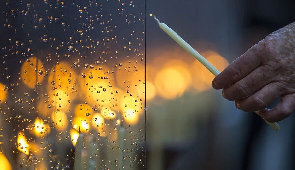 An elderly person lights a candle at the Berlin Wall memorial in Bernauer Strasse after a