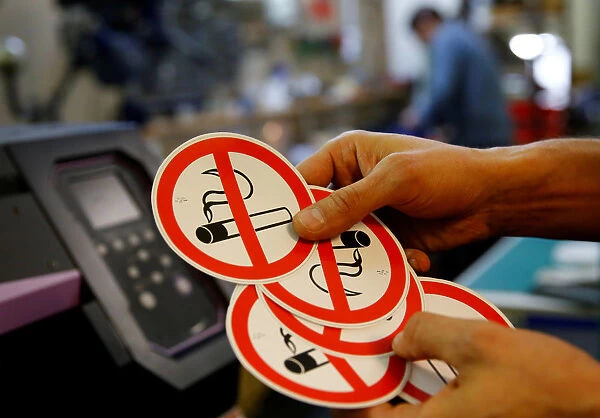 An employee shows no smoking signs in the Karas printing shop in Vienna