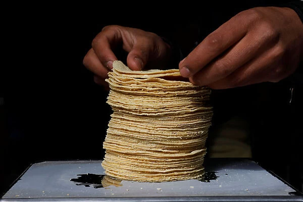 Employee weighs a stack of freshly made corn tortillas at a tortilla factory in Mexico