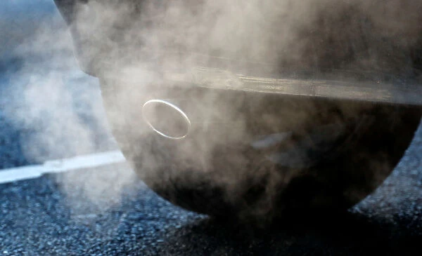 An exhaust pipe of a car is pictured on a street in a Berlin