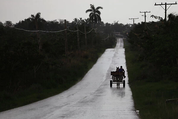 A farmer rides in a horse-drawn cart as it rains on the outskirts of Havana