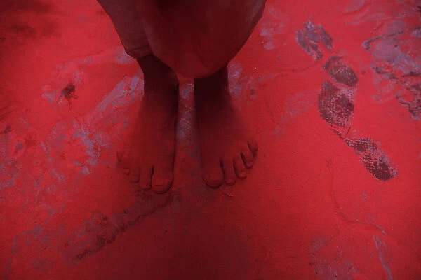 The feet of a man covered in red coloured powder are pictured during Holi celebrations
