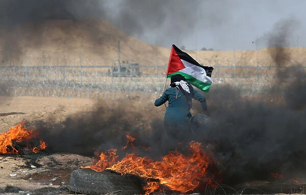 Female demonstrator carries a tire during a protest where Palestinians demand the right