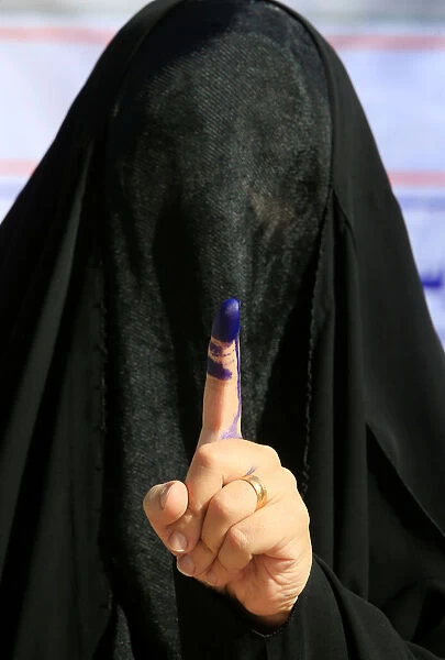 A female security member shows her ink-stained finger after casting her vote at a polling