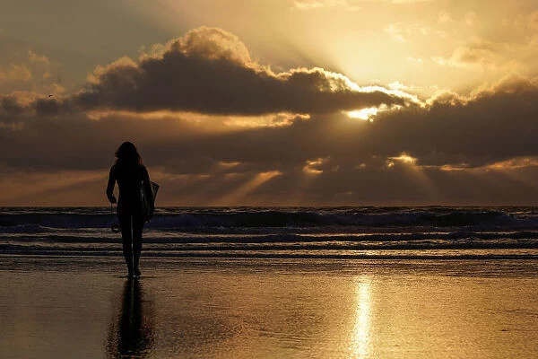 A female surfer walks out into the waves at Cardiff State Beach in Encinitas, California
