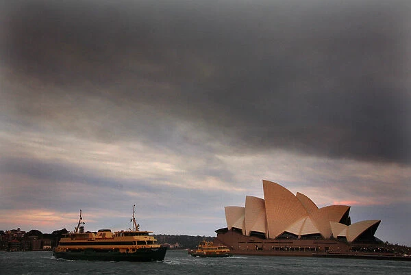 Ferries sail past the Sydney Opera House as smoke from bushfires can be seen above