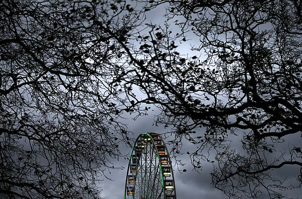 A ferris wheel is illuminated against the evening sky in Hyde Park in London, Britain